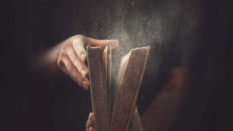 A person opening a dusty Bible.