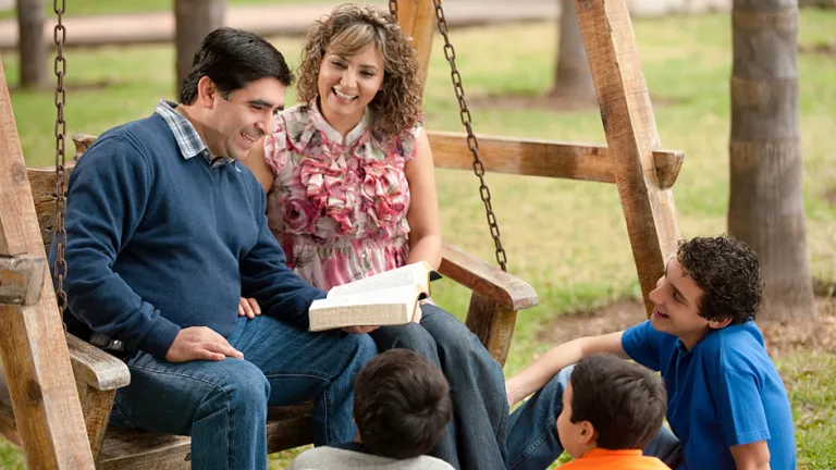 “I will put My law in their minds, and write it on their hearts; and I will be their God, and they shall be My people.” A family reading the Bible together.