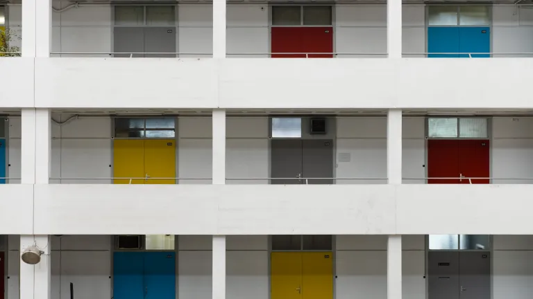 Outside of building with several floors featuring different colored doors.