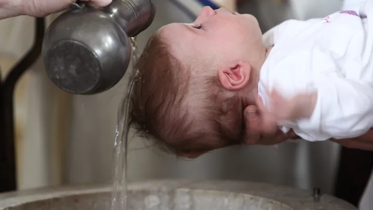 As good as the idea of baptizing an infant might sound, even parents cannot make decisions about conversion for their children. A young baby being baptized with water pouring over the child's head.