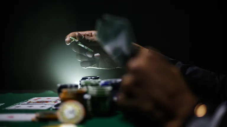 Millions of people surrender part of their paychecks each week hoping to win a fantasy life of ease and luxury. A poker player holding cards and chips.