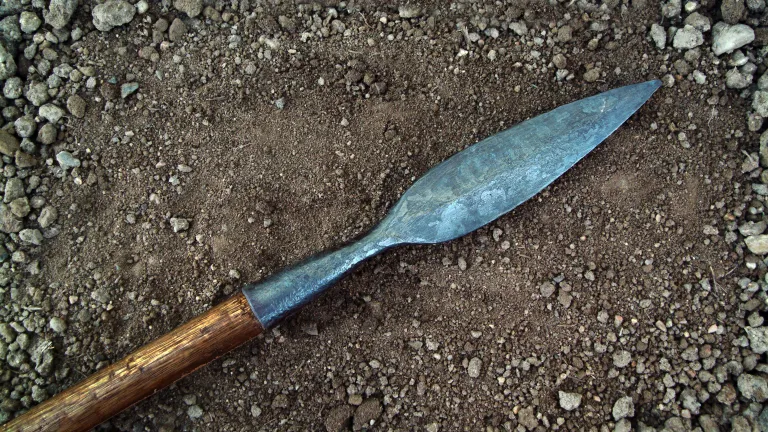 A spear lying on the dirt.