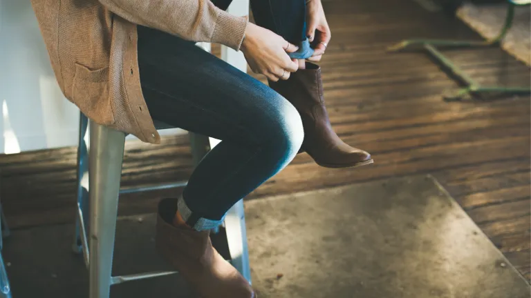 The law in Deuteronmy does not refer to women wearing pants. A woman sitting on a bench adjusting her shoes.