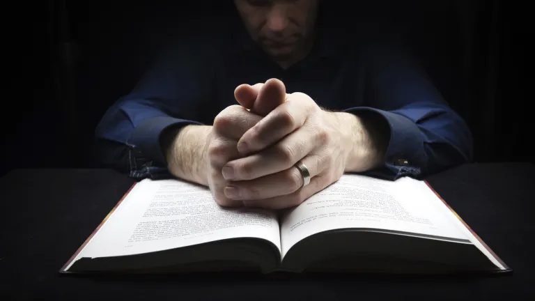 To obey God's biblical commands in a proper attitude, such as His command to remember the Sabbath and keep it holy, is not legalism. A man praying over his Bible.