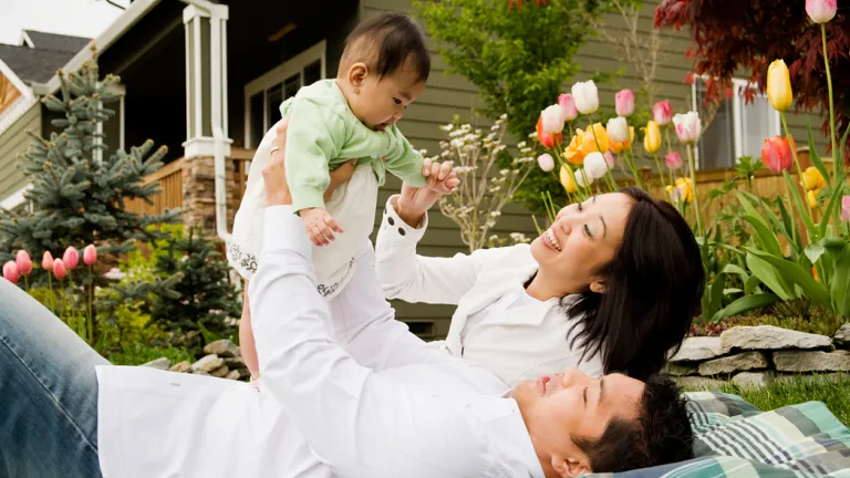 A family with a baby laying on blanket outside playing.