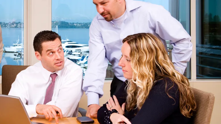 A group of people working together at a table using laptops.