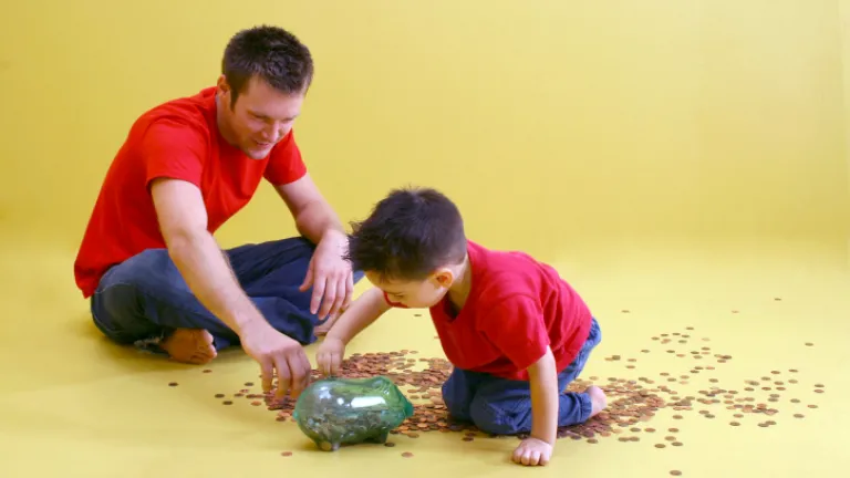A father and son counting pennies from a glass jar.