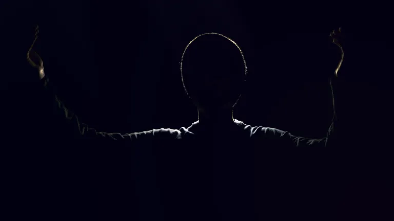 A shadow silhouette of a man with arms in the air.