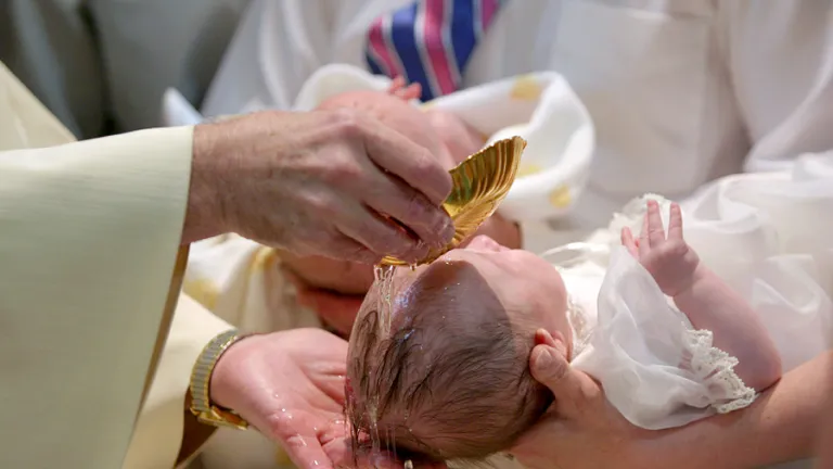 A baby being sprinkled with water.
