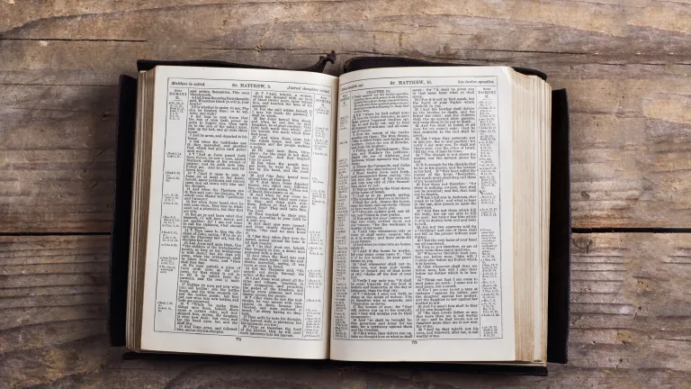 A Bible laying on a table opened to the book of Matthew.