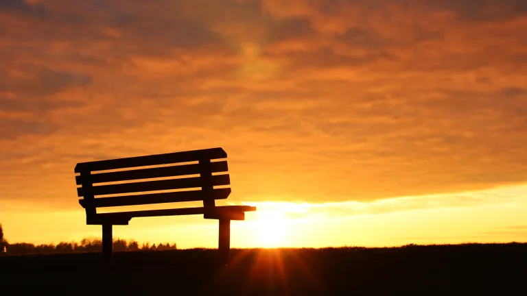 What did Christ teach His disciples to pray about the Kingdom of God? A empty bench with the sun setting.