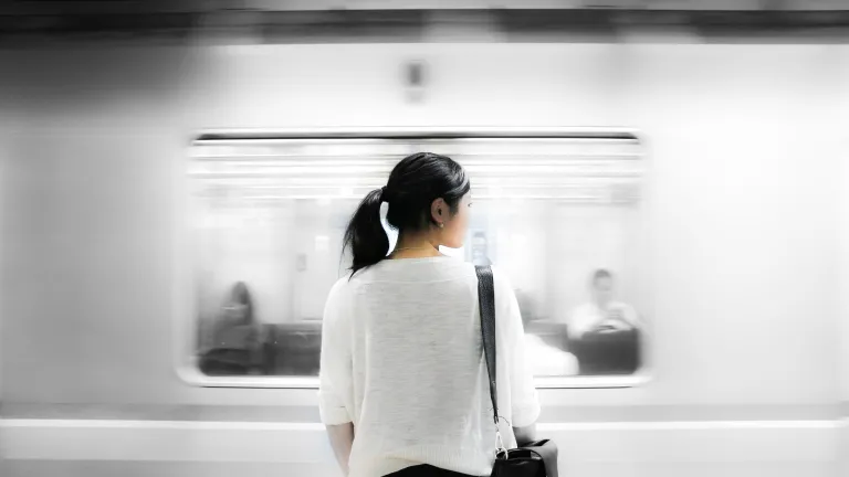Have you thought about—do you know—what God is able and willing to do for you? A woman standing has a train speeds by.