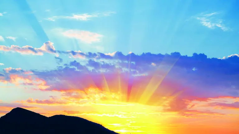Sun rays shining over hills.