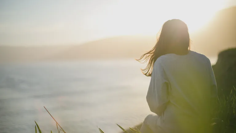 A woman looking at sunset over a body of water.