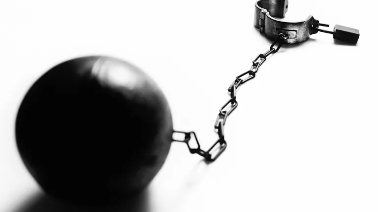 Abuse of alcohol causes untold harm to the abuser, his or her family and society. A iron ball with shackles.