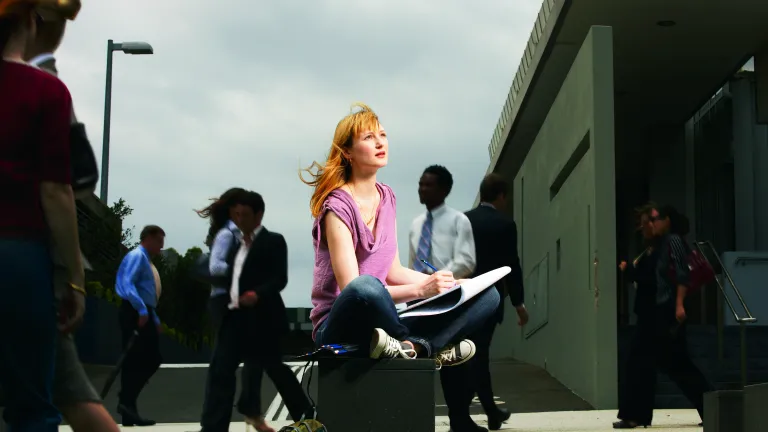 A woman sitting in a public place looking up.