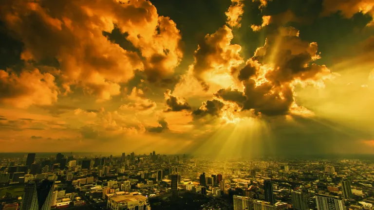 Sun rays shining through clouds on a city.