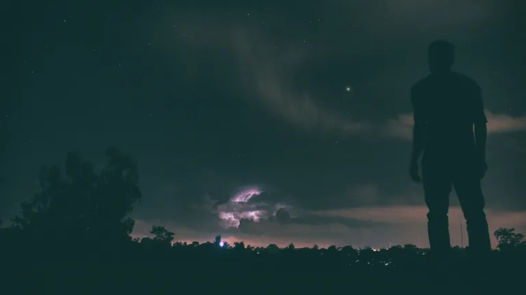 A person standing outside looking up at stars in the sky.