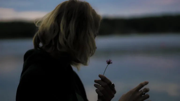 We have the assurance that even though life may be a bit rough at times, we do have an advocate–Jesus Christ. A woman holding a wilting flower in her hand.