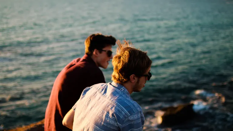 The use of curse and swear words are so commonplace in today’s world that people are no longer shocked by it. Two young men talking to each other by the ocean.