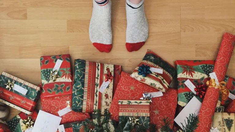 A person with socks standing right beside Christmas gifts.