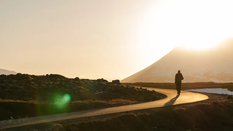 God intended human beings to ultimately be much more than angels! A person walking on a narrow road with the sun setting in the background.