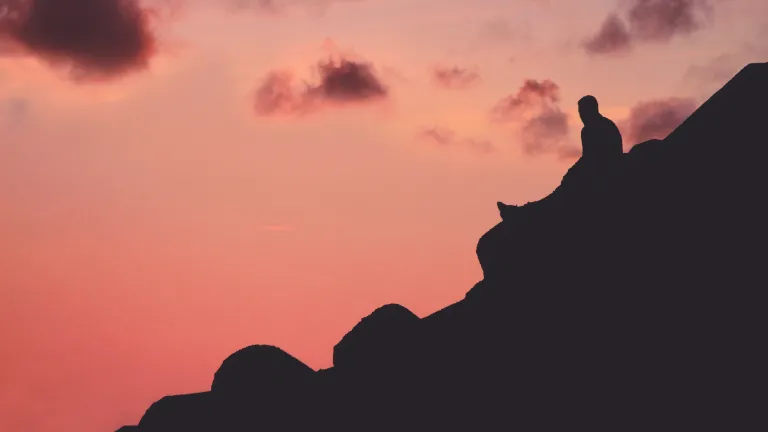 One of the signs God may be calling you is that you are beginning, however gradually, to understand the Scriptures with a depth and dimension you never experienced before. A person sitting a hill with a red sky.