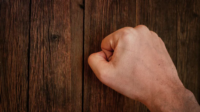 A close fist knocking on a door.