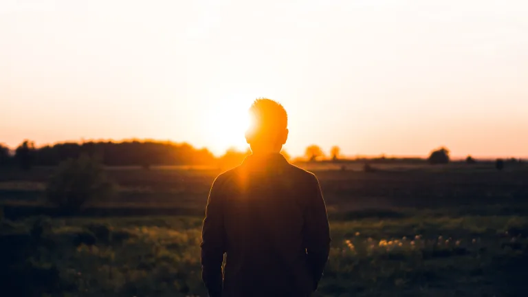 A young person watching a sunset.