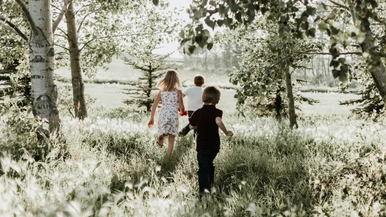 Three kids running through a field.