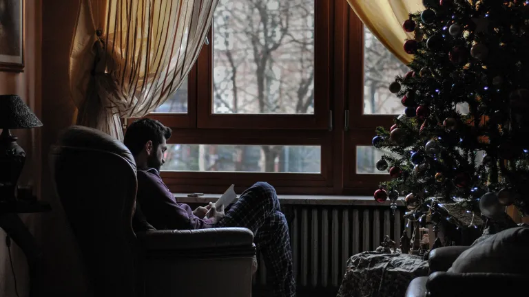 What do the major symbols of Christmas— Santa Claus, decorated trees, mistletoe—have to do with the birth of the Savior of mankind? A man sitting in a chair across from a Christmas tree.