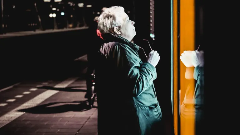 An older person looking into a store window at night.