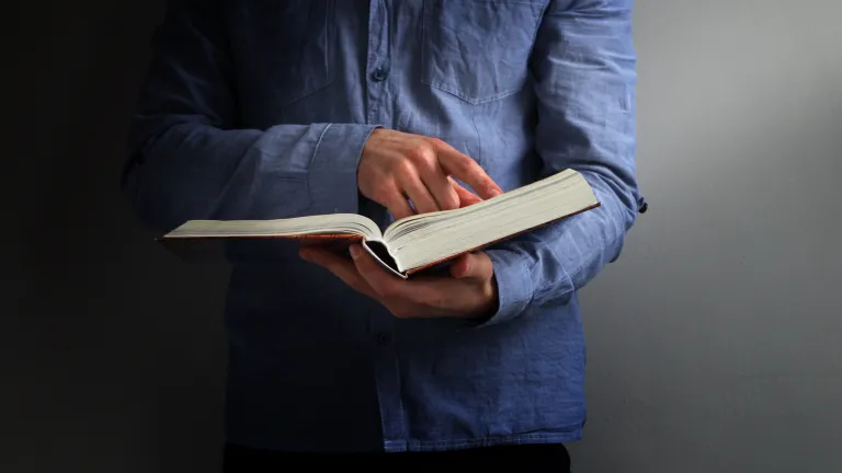 A man wearing a blue shirt holding a Bible.