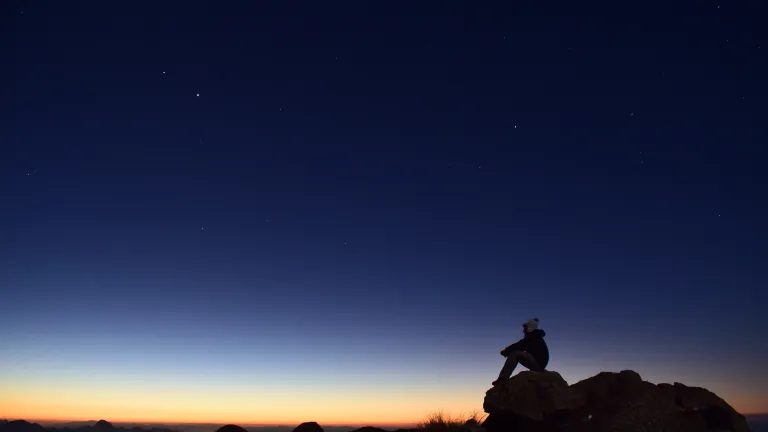 May we all develop that vital and proper fear of God that leads to loving Him and others and avoid cowardly fear by putting God first in our lives. This is what the Bible means in telling us to have the fear of God! A person sitting on a rock at sunset.