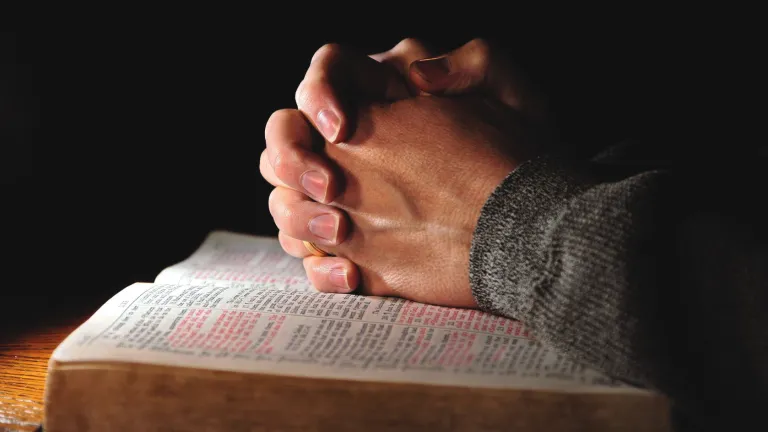 It’s never too late to repent and surrender your life to God. No matter what your sins, or what kind of situation you may find yourself in. Clasped hands on top of an open Bible.