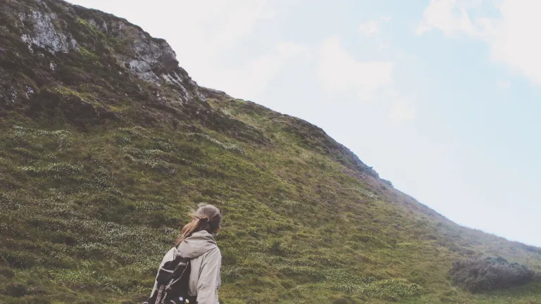 A woman beginning a hike up a steep incline.
