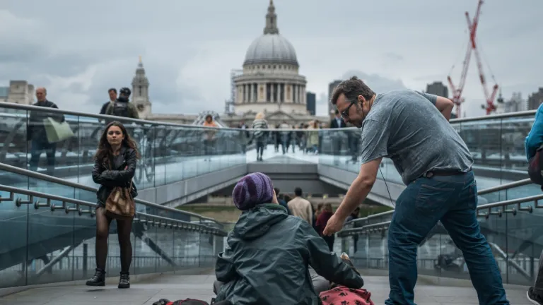 A man giving a donation to a homeless person.