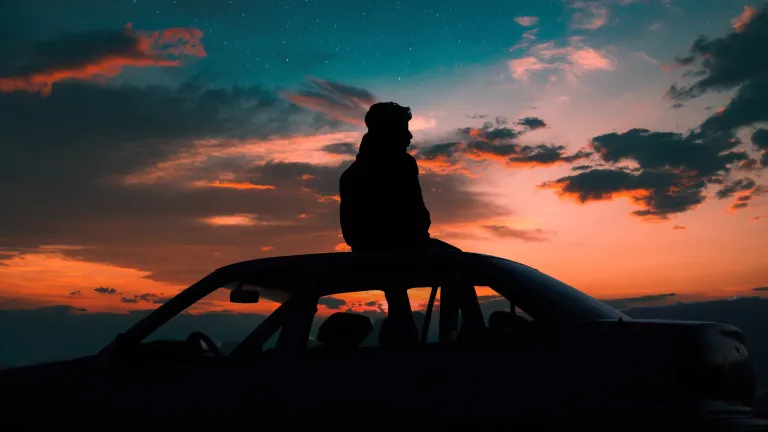 It is a blessing to know that once you have truly done your best, you can leave the rest and not worry about it. A young man sitting on the top of a car watching the sunset.