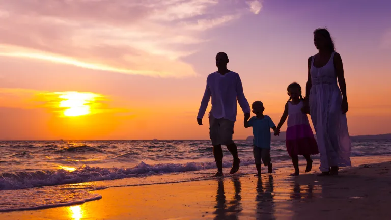 Parents should make time for their children since the greatest gift they can give to their children is themselves and their time. A family of four walking on the beach at sunset.