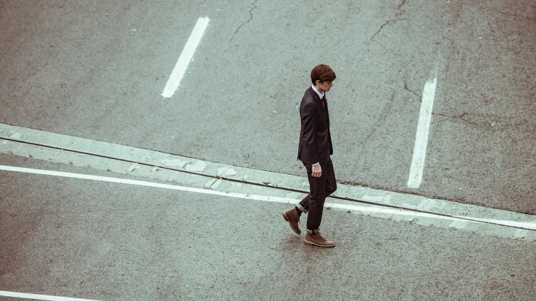 The real poverty humans experience is that of the heart. That is often irreparable. That is the bank account to which we need to continually add a little each day to maintain a good balance. A young man in a suit walking across a road.