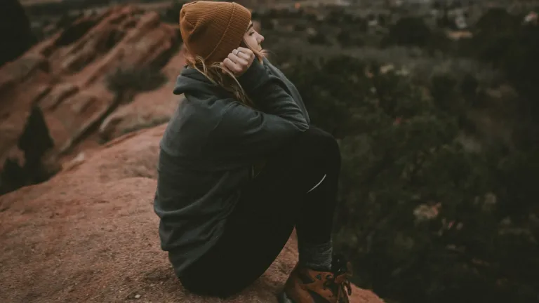 A young woman sitting on a boulder.