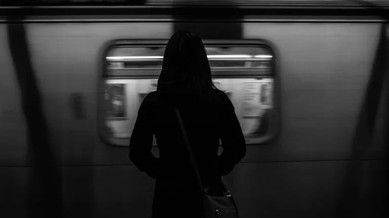 A woman standing by a subway train as it passes by.