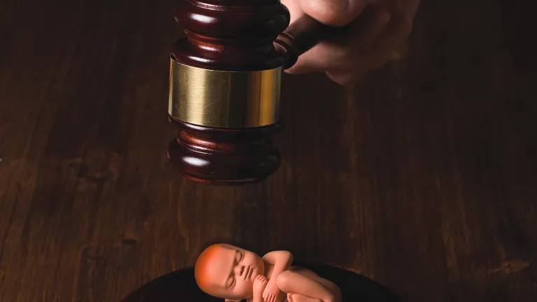 The abortion debate is a matter we should remain acutely aware of. A nation’s tolerance of the murder of the innocent is revealing of its morality and character. An illustration of newborn baby laying below a judge's gavel.