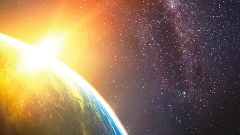 “In the beginning was the Word, and the Word was with God, and the Word was God . . . All things were made through Him, and without Him nothing was made that was made.” Sun rays shining past earth.
