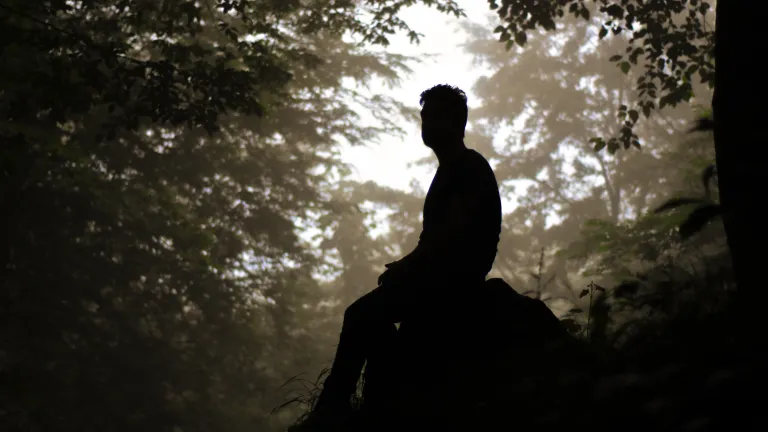 Silhouette of man sitting on a rock.