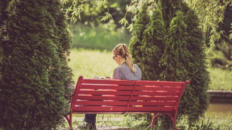 We prove we have faith by how we live after we accept Jesus Christ! This living and active faith involves effort to obey and trusting God to empower us and help us succeed—resulting in works of obedience being produced. A woman reading while sitting on a red bench.