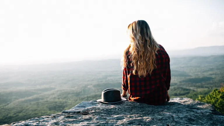 A young woman sitting on a rock.