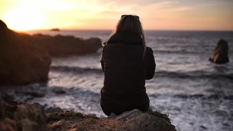 We who are the recipients of God’s incomparable gifts of grace are obligated in turn to become people who personify grace and willingly and gratefully extend that grace to others for the benefit and blessing of all. A woman sitting on a rock looking out over water.
