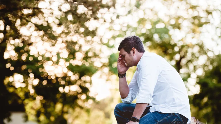 A man with his head in his hands as if he was praying.