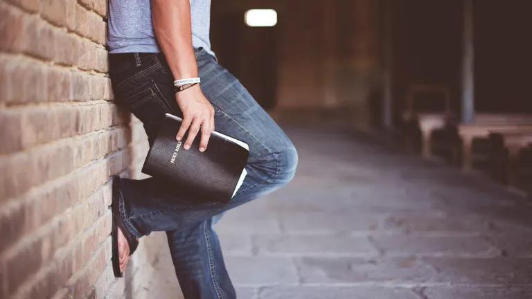 The religious symbolism of the cross has its roots in ancient paganism. It became a symbol of Christianity only after the time of Constantine. Man holding Bible.
